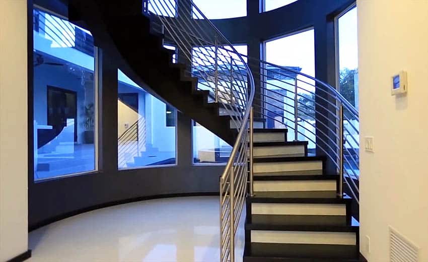 A winding staircase with large windows and steel type railings