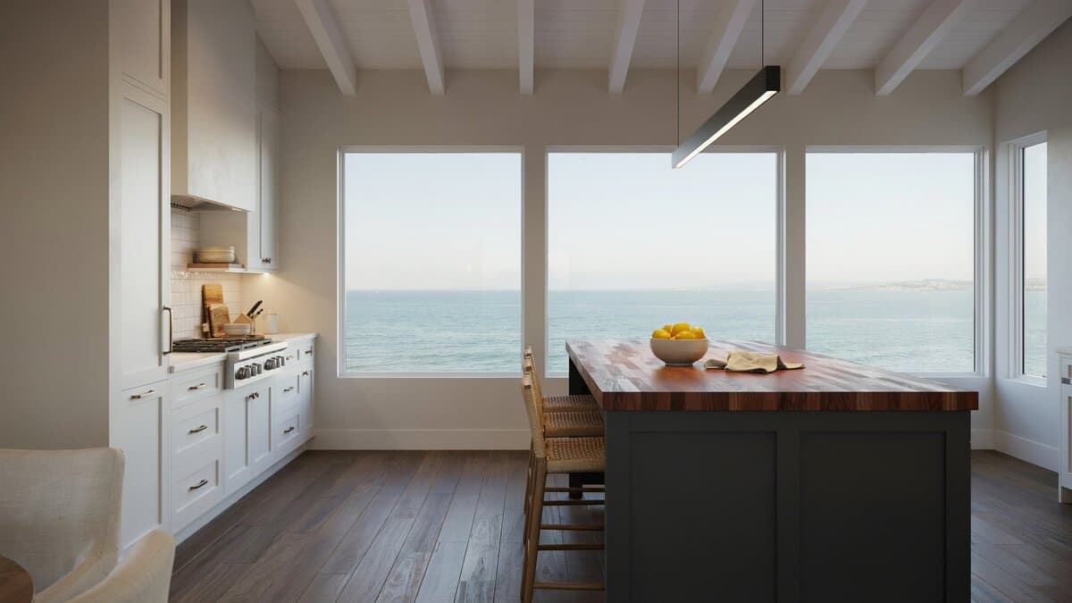 Tall ocean facing windows above a dark island with red wood block top