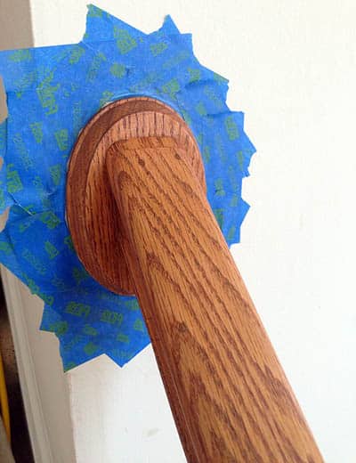 Taping around stair railing to protect wall paint
