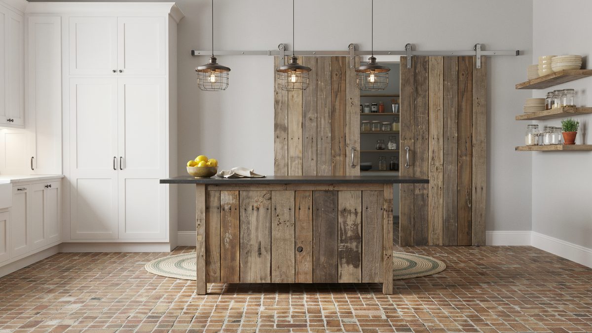 Barn board island on brick flooring below a sliding pantry door on steel track