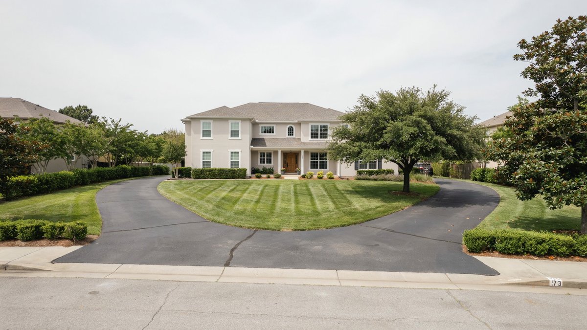 U shaped asphalt driveway with two street entrances around a lawn at a brick colonial