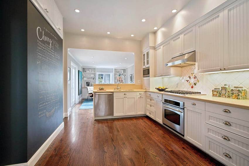 White kitchen with beadboard cabinets and large blackboard wall