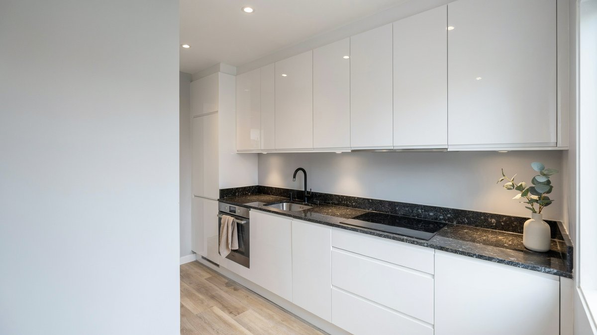 White gloss cabinets with dark speckled granite counters along a gray wall