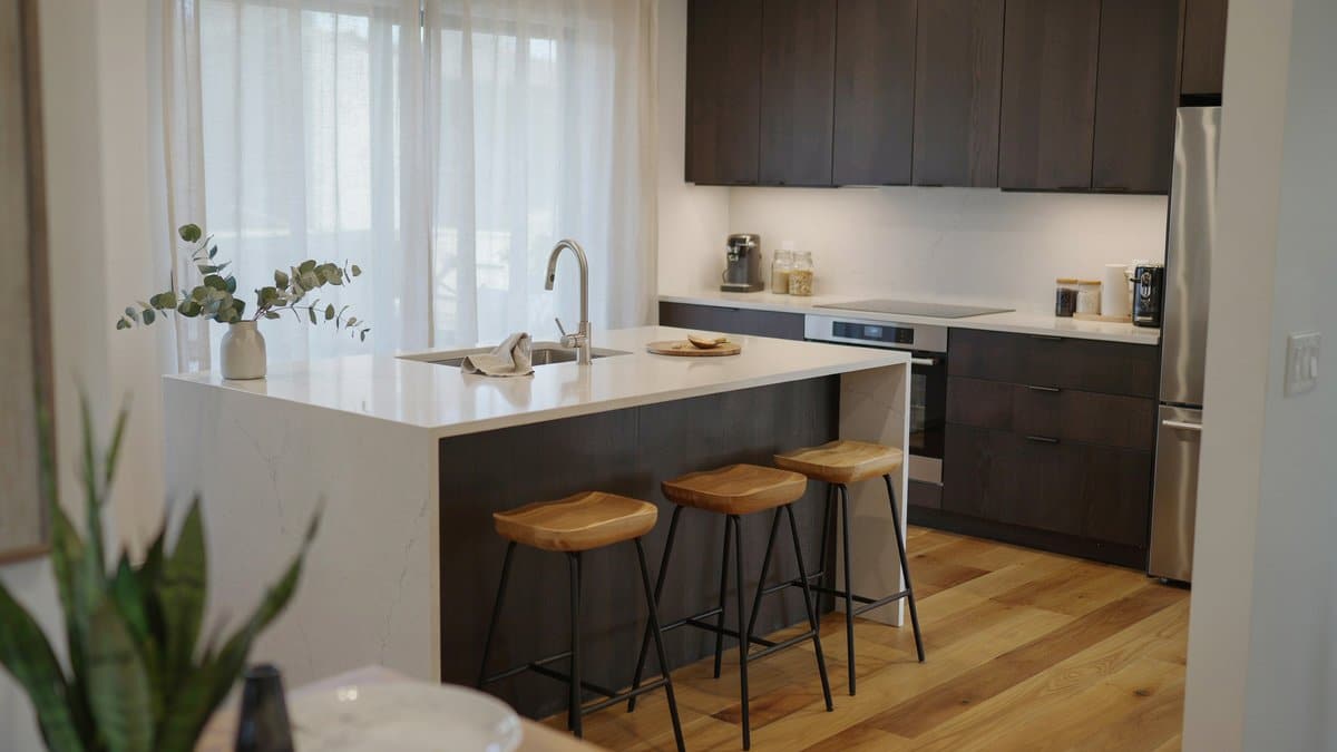 Wenge wall cabinets with a white island and three wooden stools