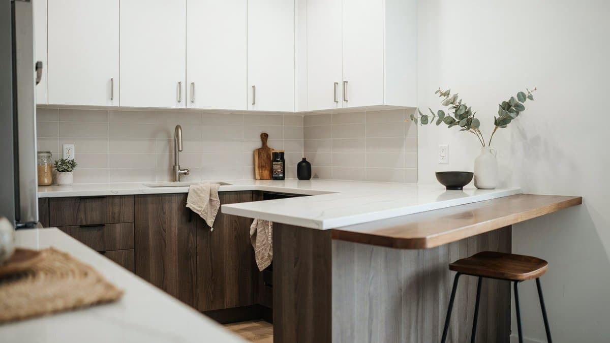 White upper cabinets over dark wood bases with a wood bar ledge