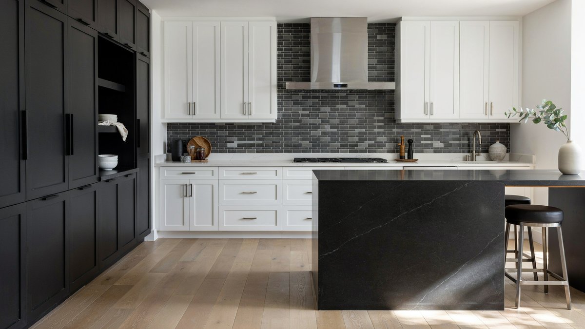 Black island and gray tile backsplash paired with white upper cabinets