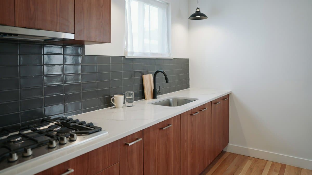 Chestnut wood cabinets with white quartz counters and dark gray glass tile