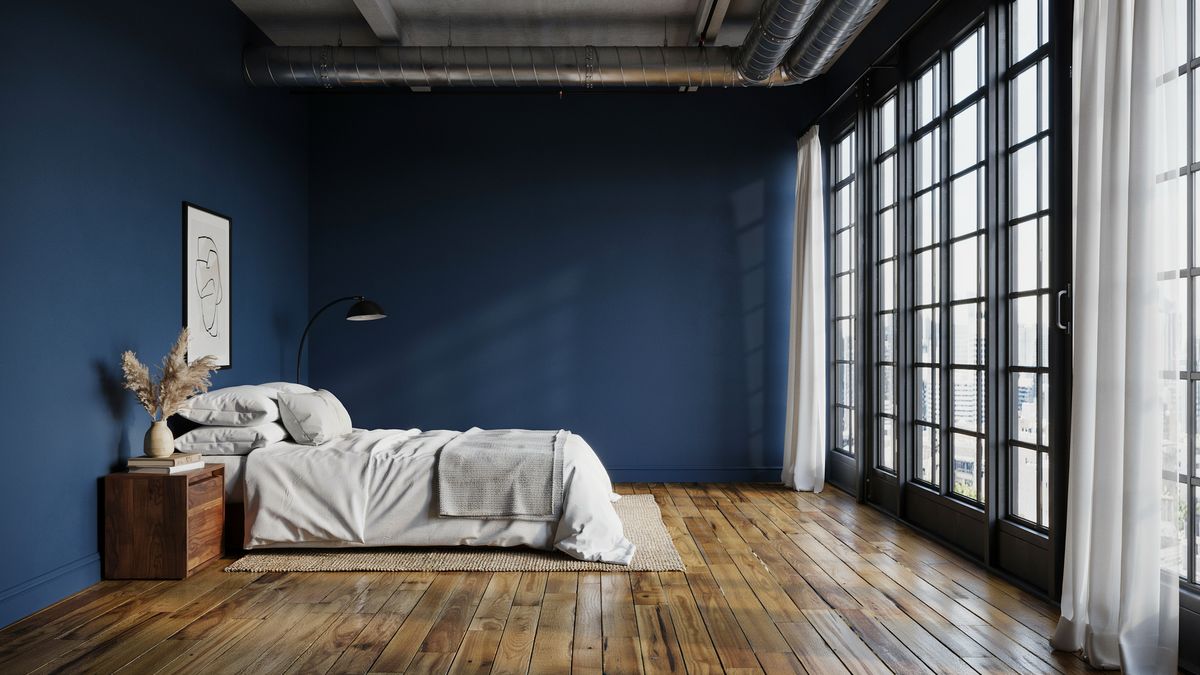 Navy blue loft bedroom with exposed ductwork and tall industrial windows