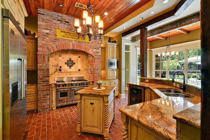 Kitchen with weathered look cabinetry and brick accent wall