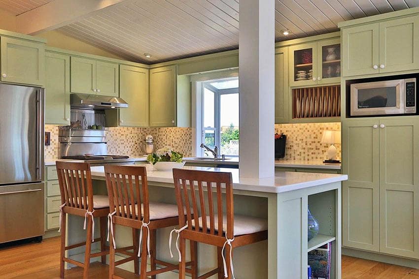 Kitchen with green cabinets and island support post