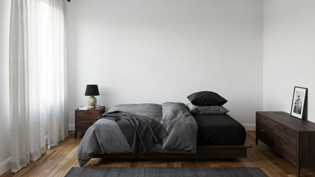 White bedroom with charcoal and black bedding on a dark wood platform bed