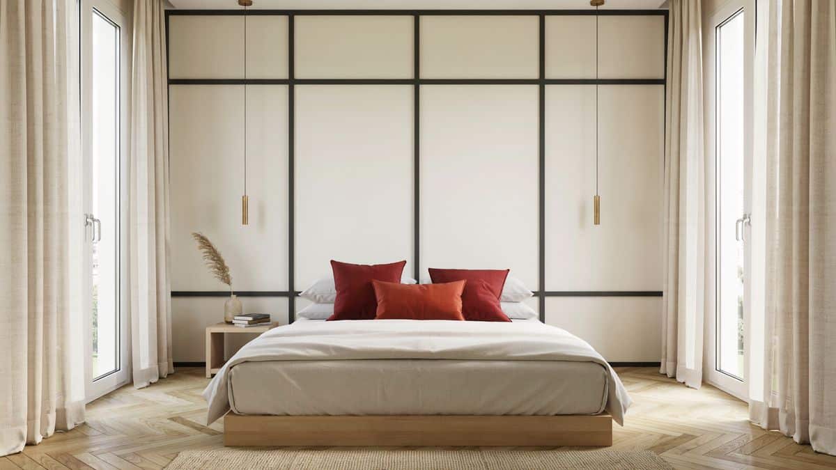 Bedroom with black grid panel accent wall, white comforter and red pillows