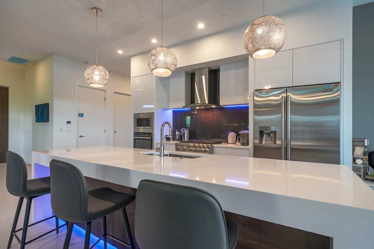 Kitchen with large island, wire globe lighting and neon backlights.