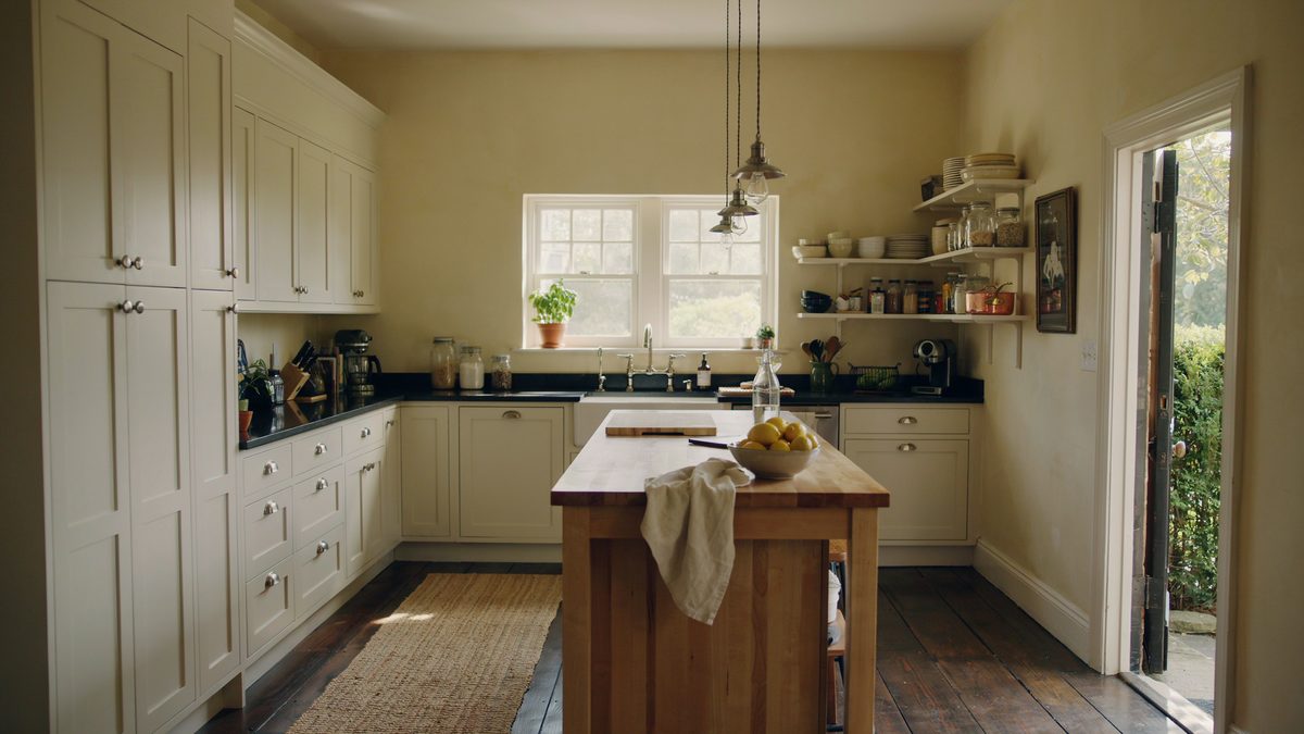 Warm yellow walls surround cream cabinets and a butcher block topped island