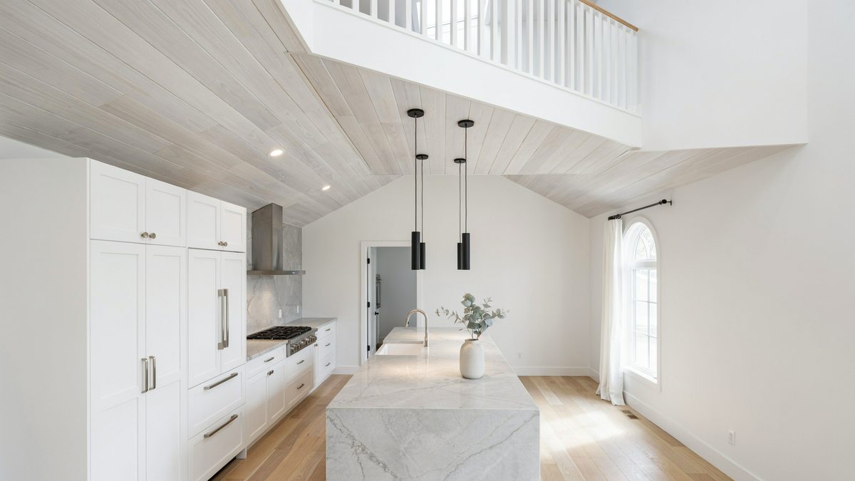 Vaulted plank ceiling and upper loft above a bright all white kitchen