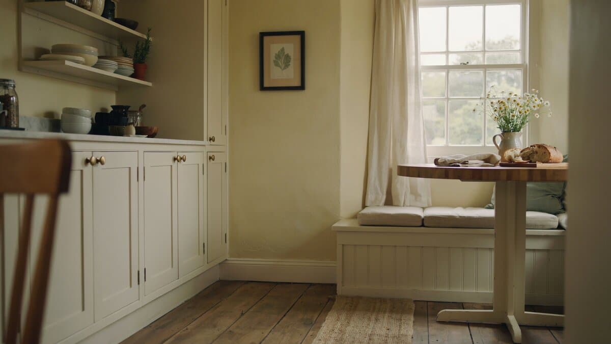 Neutral yellow farmhouse walls beside a window seat breakfast table