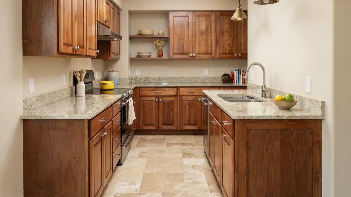 Travertine tile floor and beige granite counters set against rich oak cabinetry