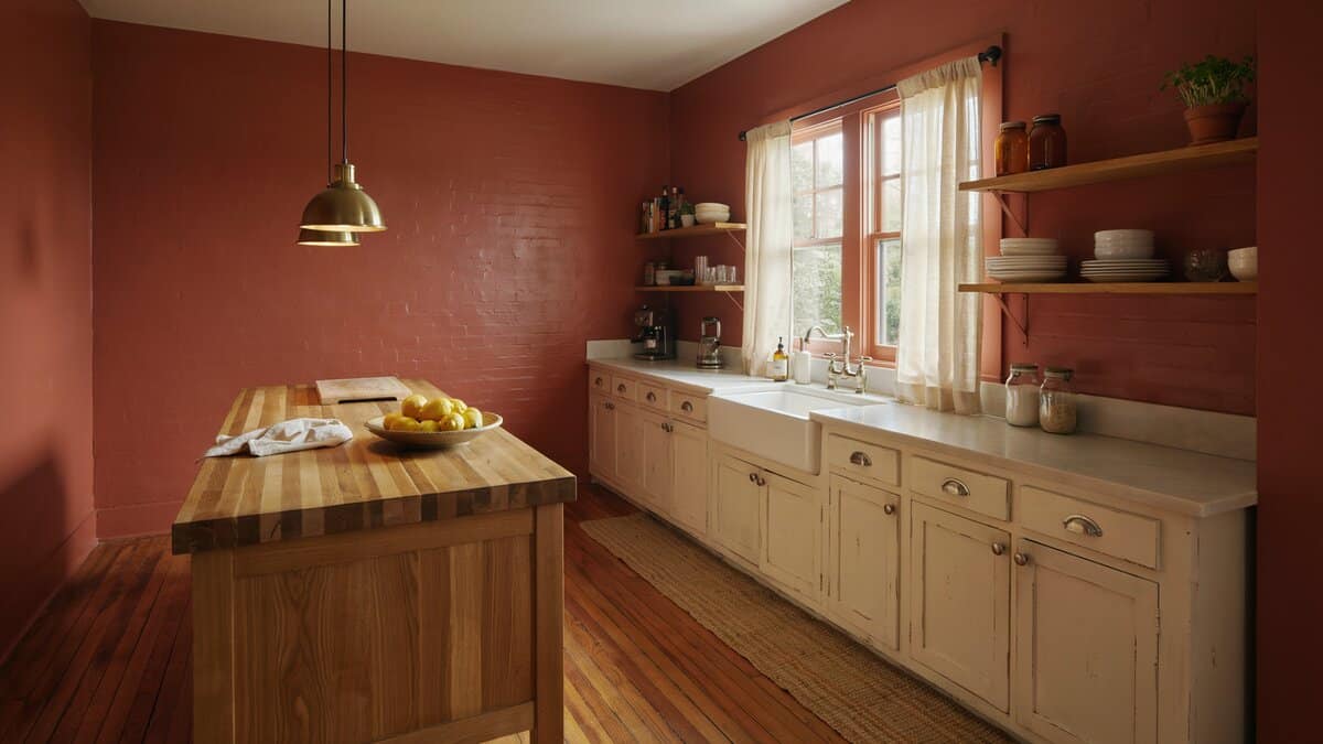Brick red walls with antique white cabinets and warm cherry wood flooring