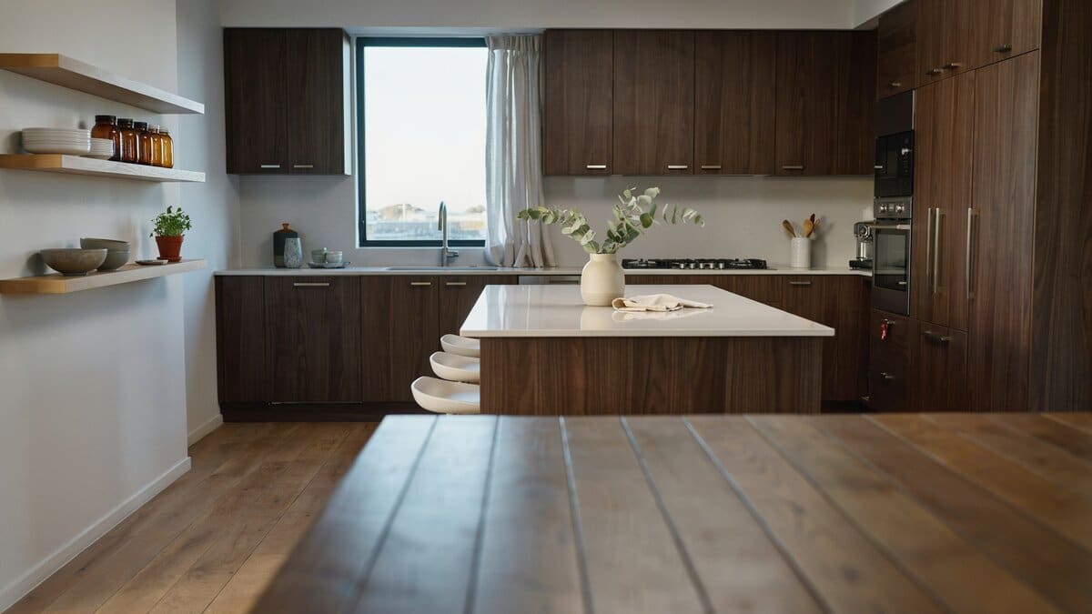 Floating oak shelves and dark walnut cabinets framing a white stone breakfast bar island