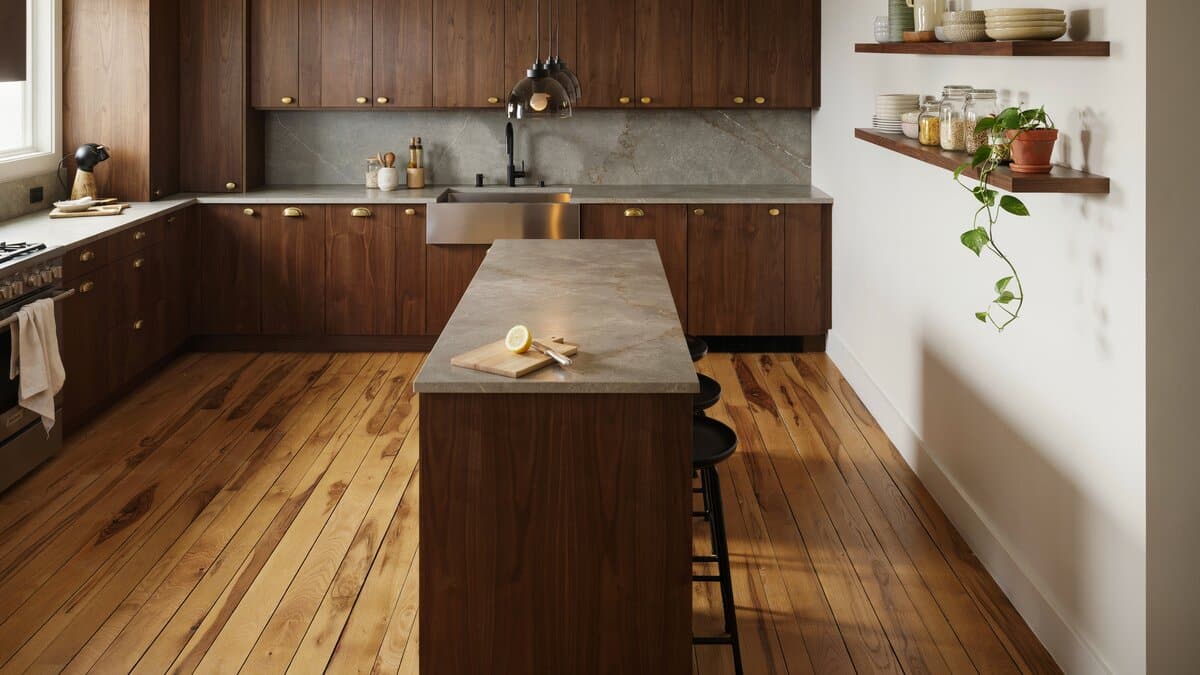Dark walnut cabinets and a long stone topped island resting on wide plank wood floors