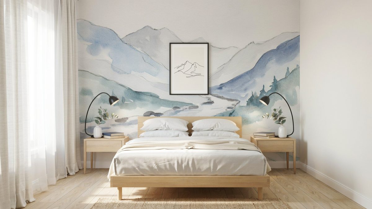 Watercolor mountain mural in soft blue behind a light oak platform bed