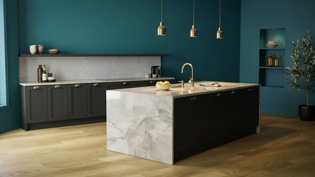 Deep teal walls and black cabinets around a natural stone island on wood flooring