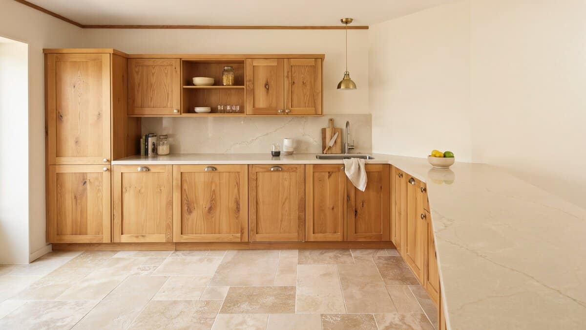 Golden oak cabinets against beige walls with a long counter and travertine floor tiles