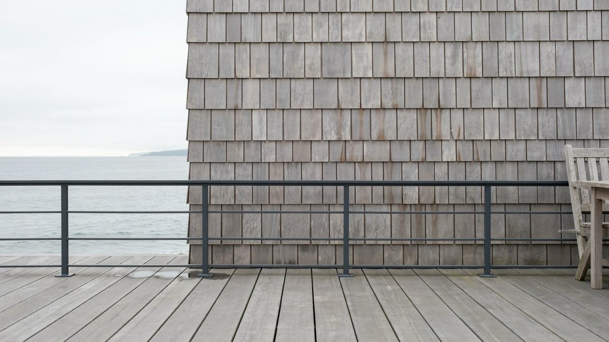 Coastal deck with light gray composite planks and thin aluminum railing