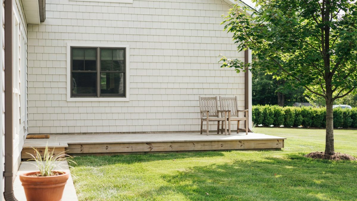 Pine platform deck with pale knotty boards and two wood chairs at the corner