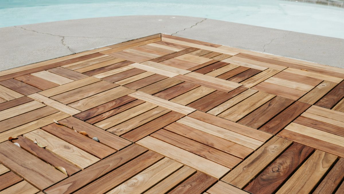 Interlocking wood deck tiles snapped together beside a swimming pool edge