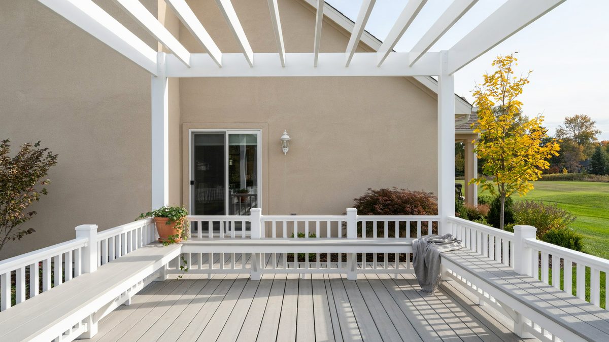 White vinyl deck with a matching vinyl pergola and benches along the railing
