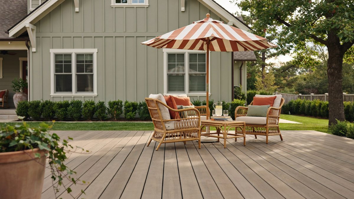 Composite deck behind a craftsman house with rattan furniture and an umbrella