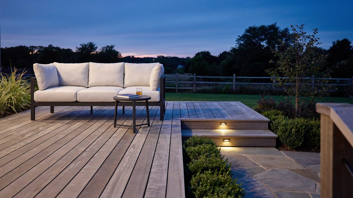 Deck at dusk with strip lighting under the perimeter edge and a white loveseat