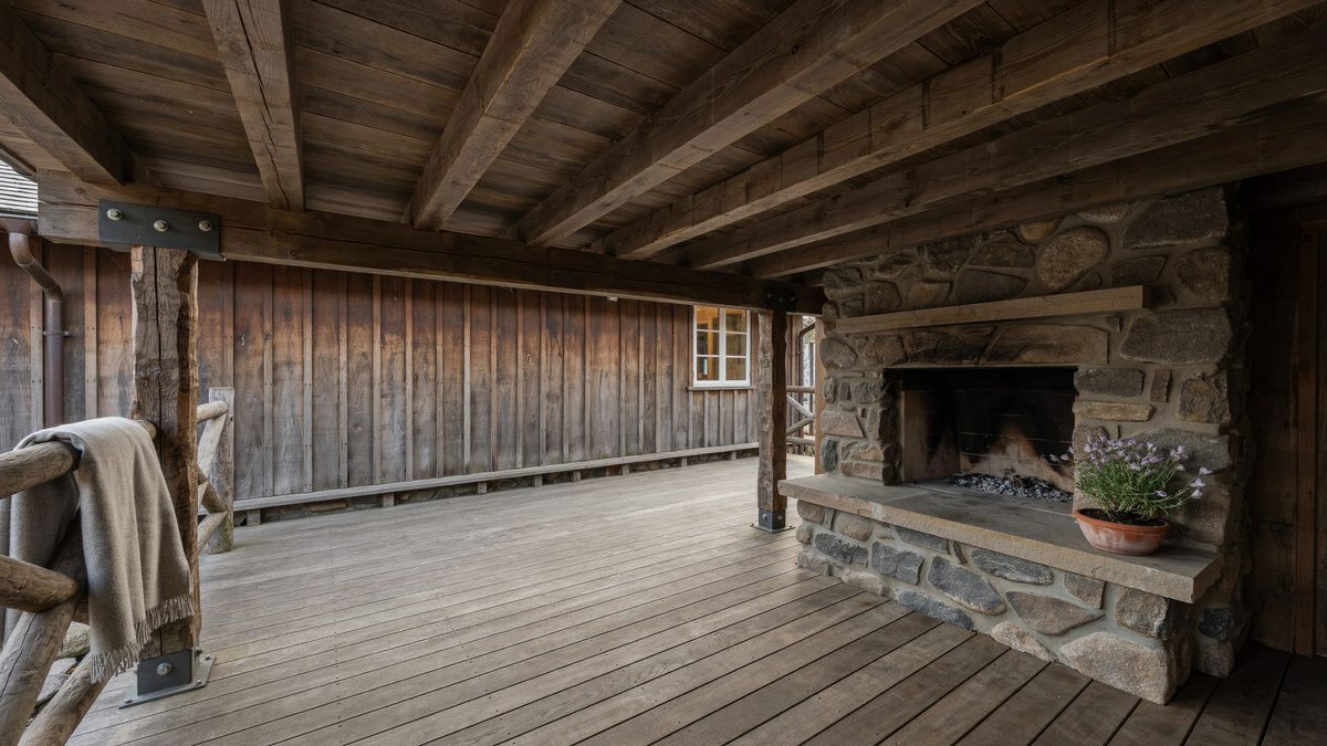 Rustic deck with exposed timber beams and a stone outdoor fireplace