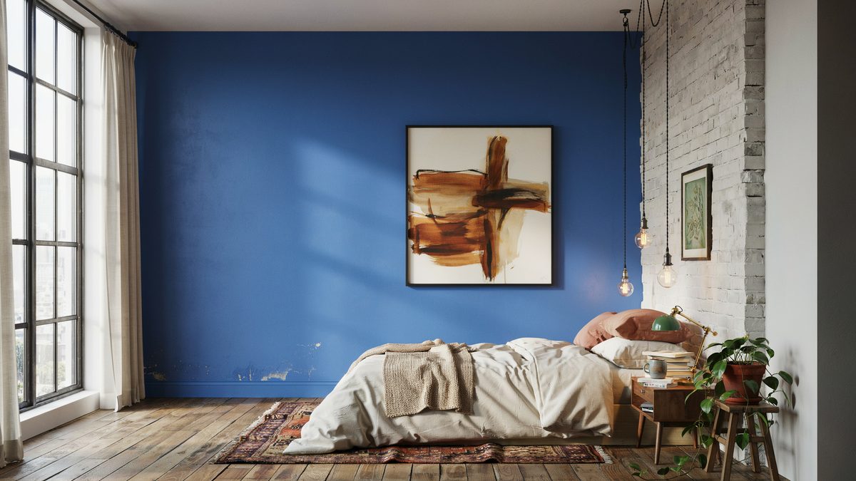 Cobalt blue loft wall with a large abstract canvas and hanging Edison bulbs