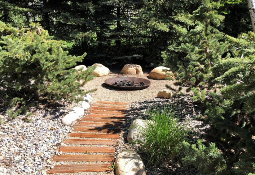 Backyard copper fire pit with gravel sitting area and wood steps