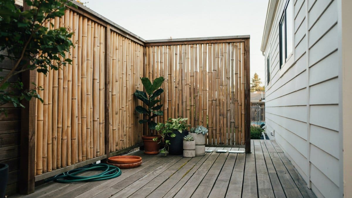 Bamboo pole screening wrapping a small deck beside potted plants