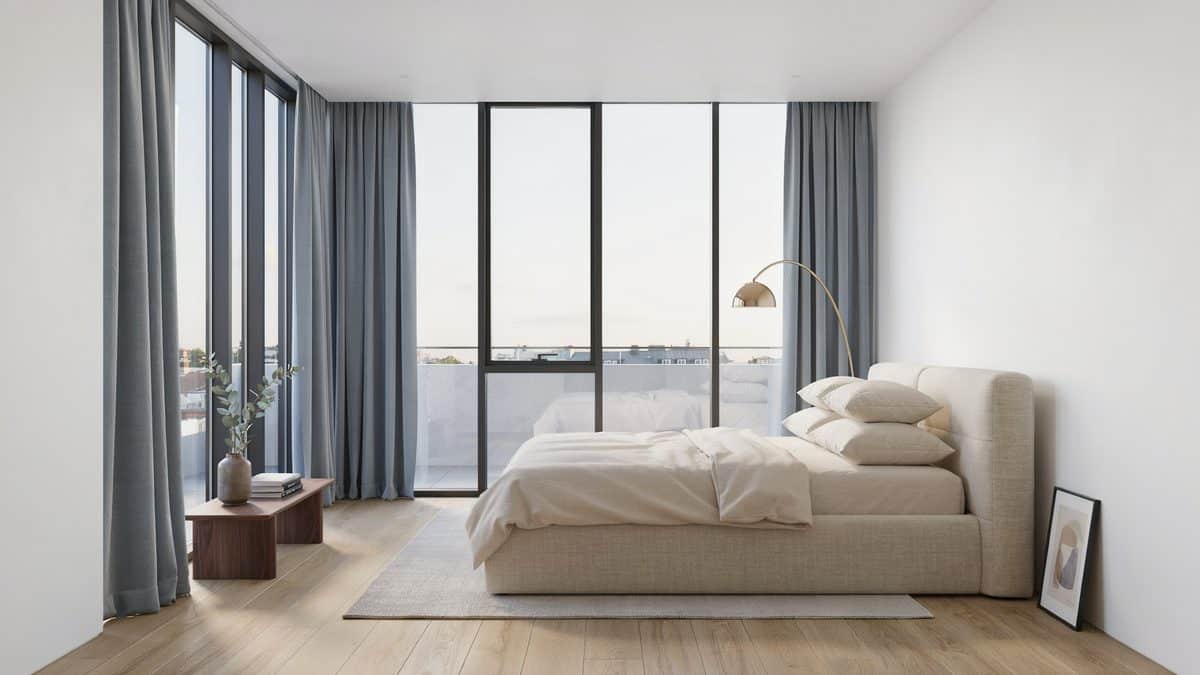 White walls with floor to ceiling glass, gray drapes and a low platform bed