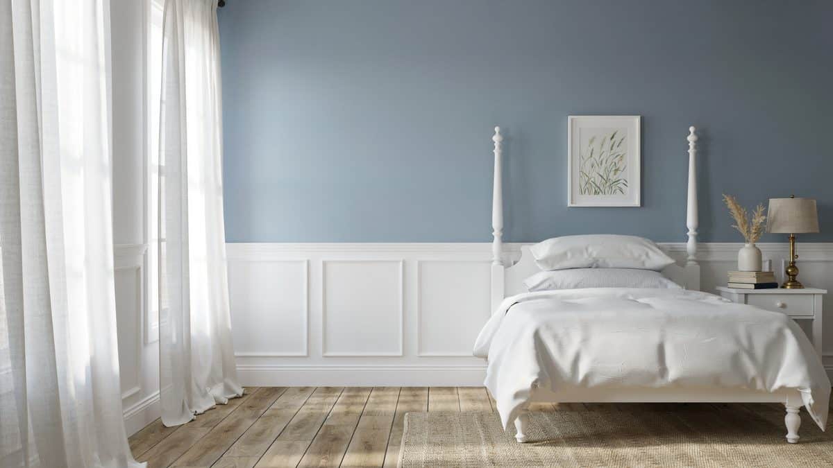 Blue paint above white wainscoting panels with a white four poster bed