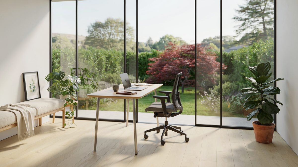 Sunroom office with floor to ceiling glass looking out on a green garden