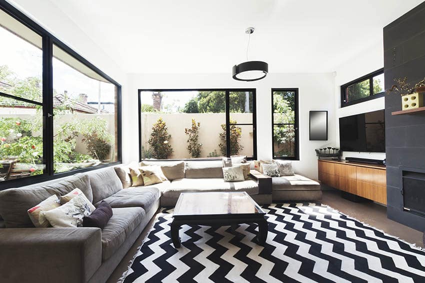 Contemporary living room with bold area rug gas fireplace black accent tile black framed windows