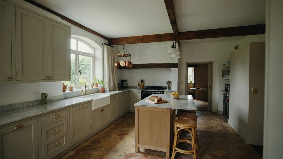 Muted green cottage cabinets with marble counters and an oak breakfast bar island