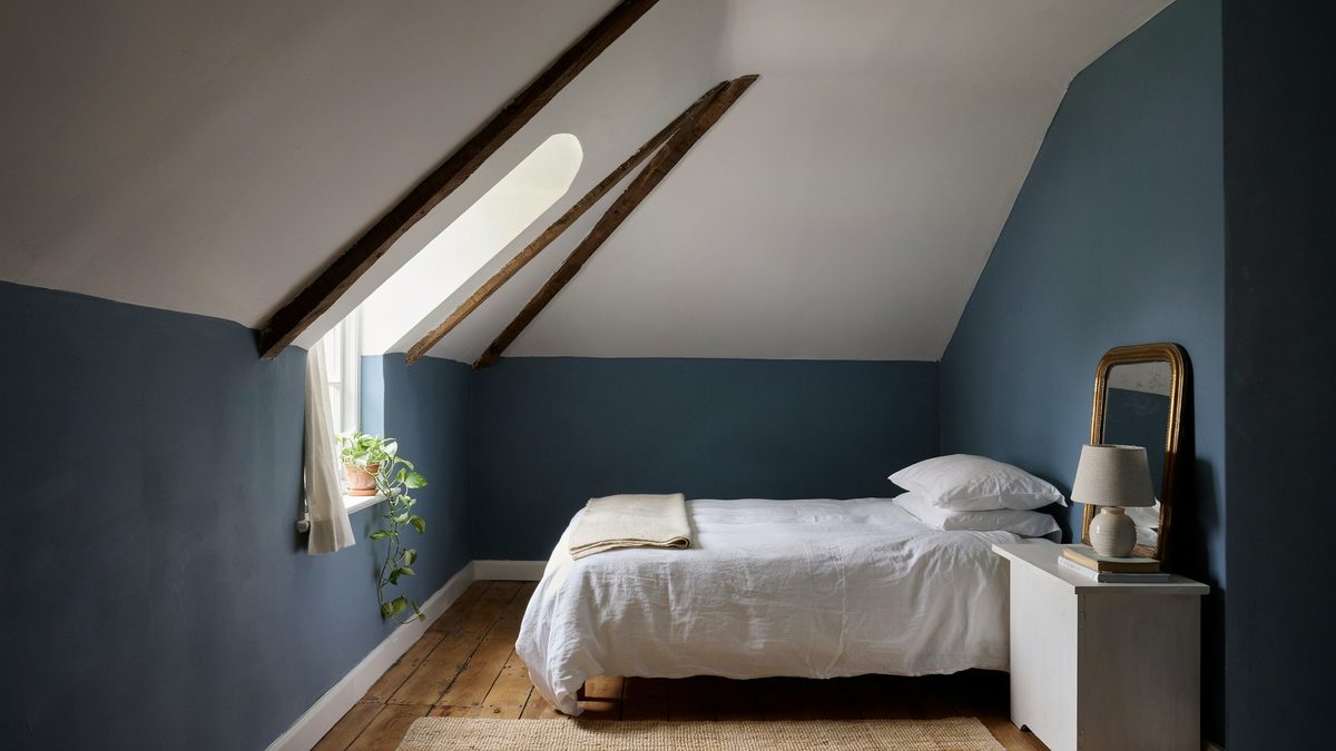 Attic room with slate blue walls, sloped white ceiling and a wood beam
