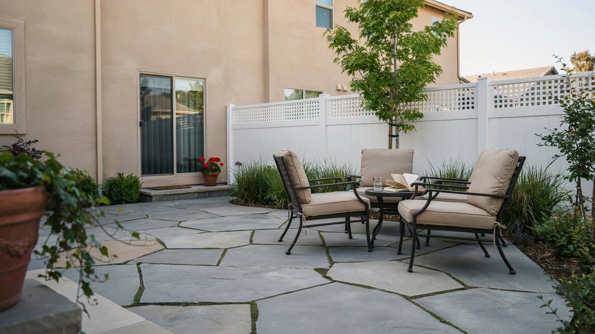 White vinyl lattice top fence around a flagstone seating patio