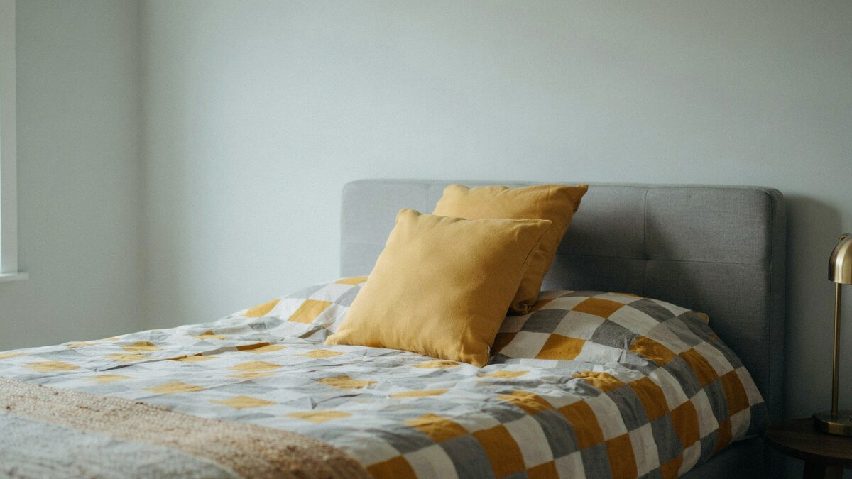 Close view of a geometric gray and yellow comforter against a gray headboard