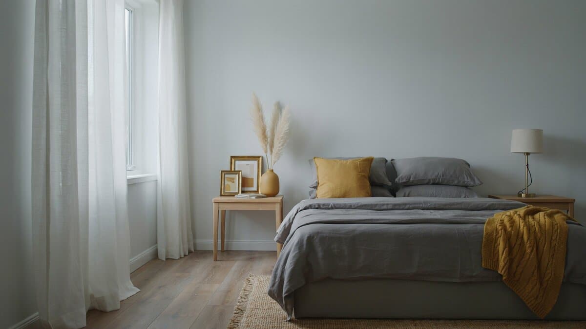 Picture frames and a mustard throw add warm accents to a gray bedroom