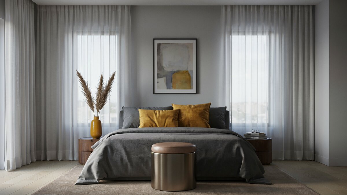 Round metallic ottoman sits at the foot of a charcoal bed with yellow pillows