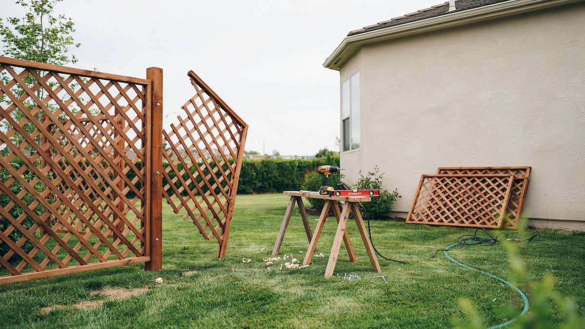 Lattice panels and tools mid installation in a grassy yard