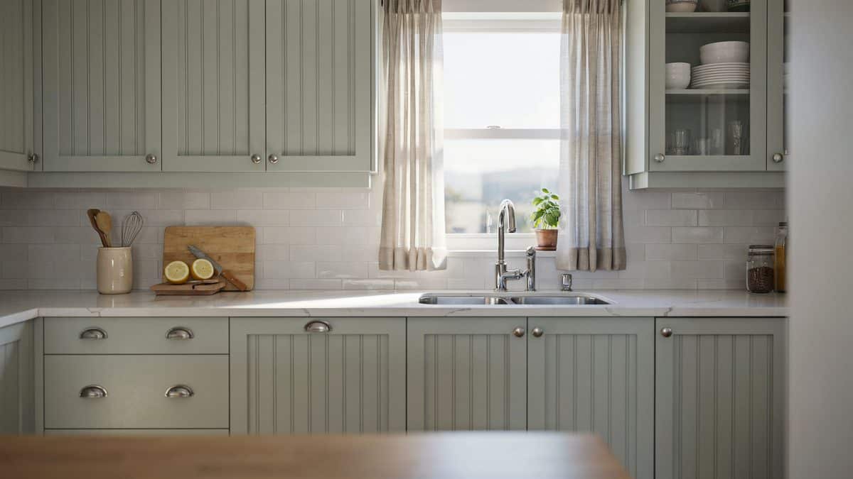 Pale green beadboard doors with cup pulls beside a curtained farmhouse window