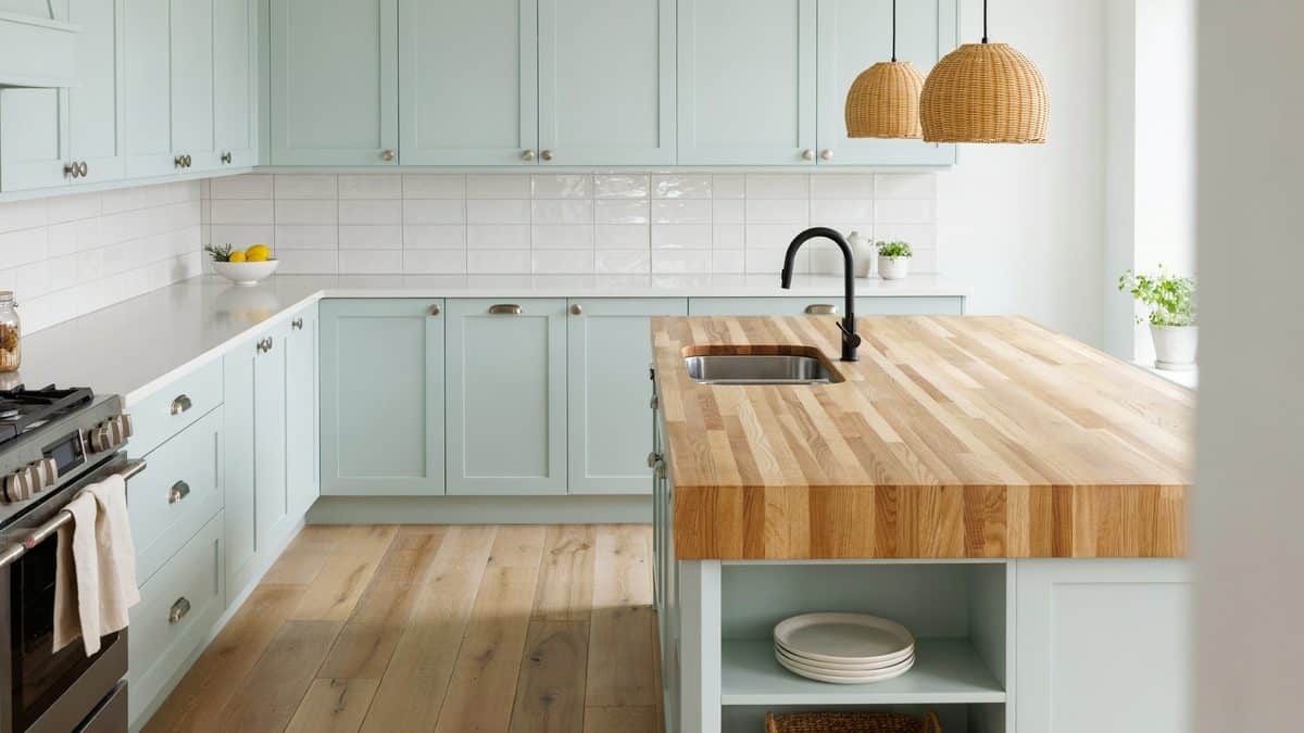Mint cabinets meeting a thick butcher block peninsula with woven pendant lights
